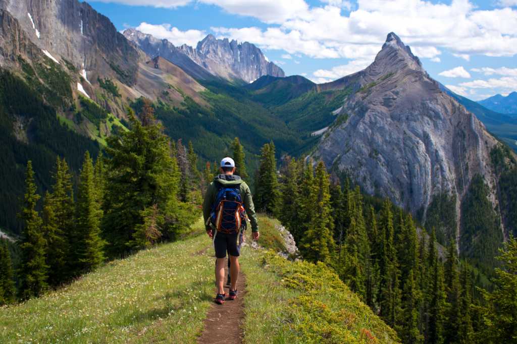 Healthy young man and a woman hiking  and enjoying the view from the top of King Creek Ridge, Kananaskis Country, Alberta, Canada on a bright sunny day. Back packing in the Canadian Rockies.